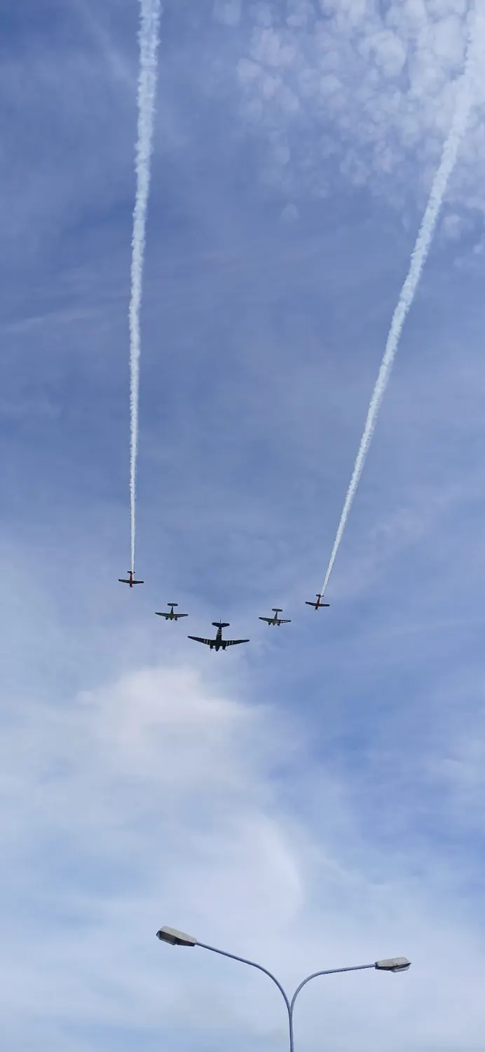 Four propeller aircraft in formation leaving smoke trails across the sky