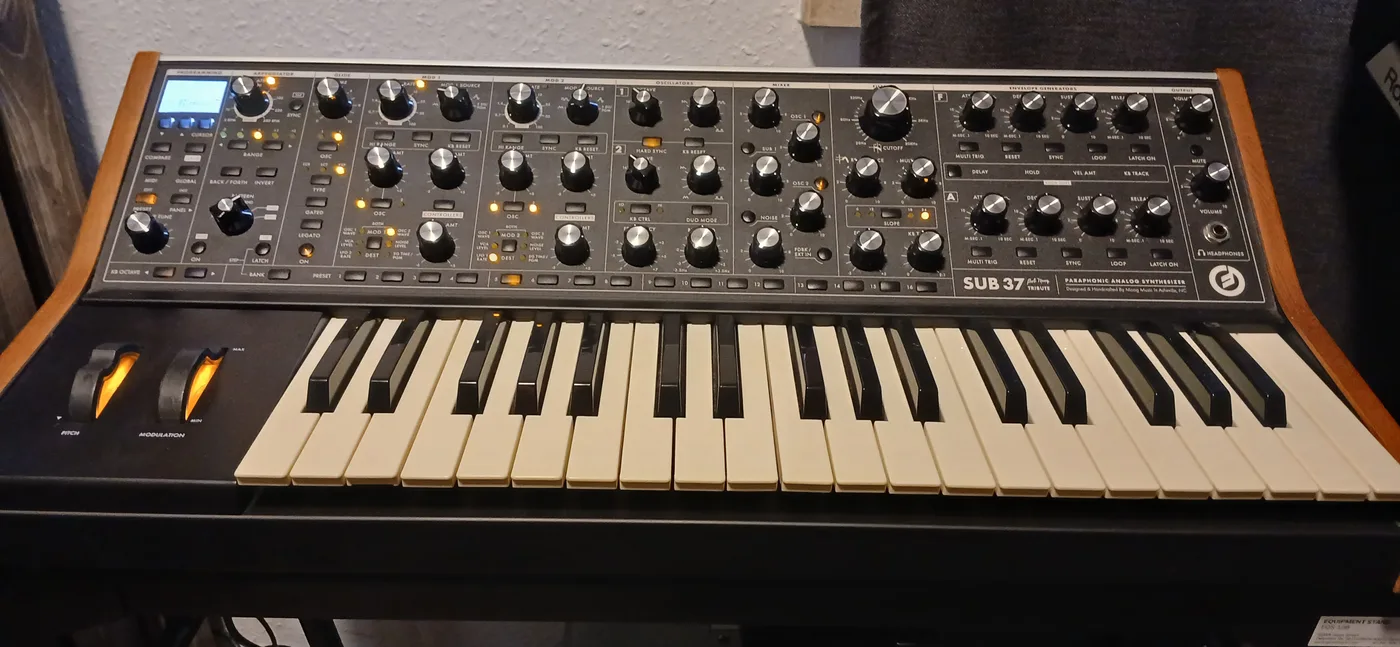 A Moog Sub 37 analogue synthesiser on its stand in the studio, lit by its own panel LEDs