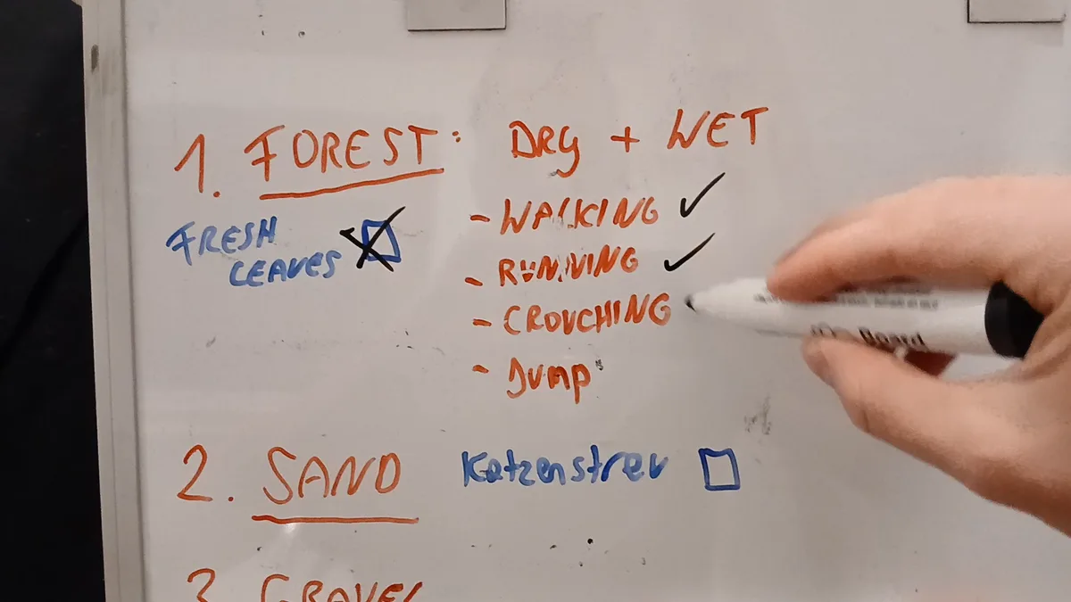 A hand ticking off a whiteboard session plan: forest dry and wet with walking, running, crouching and jumping, then sand and gravel